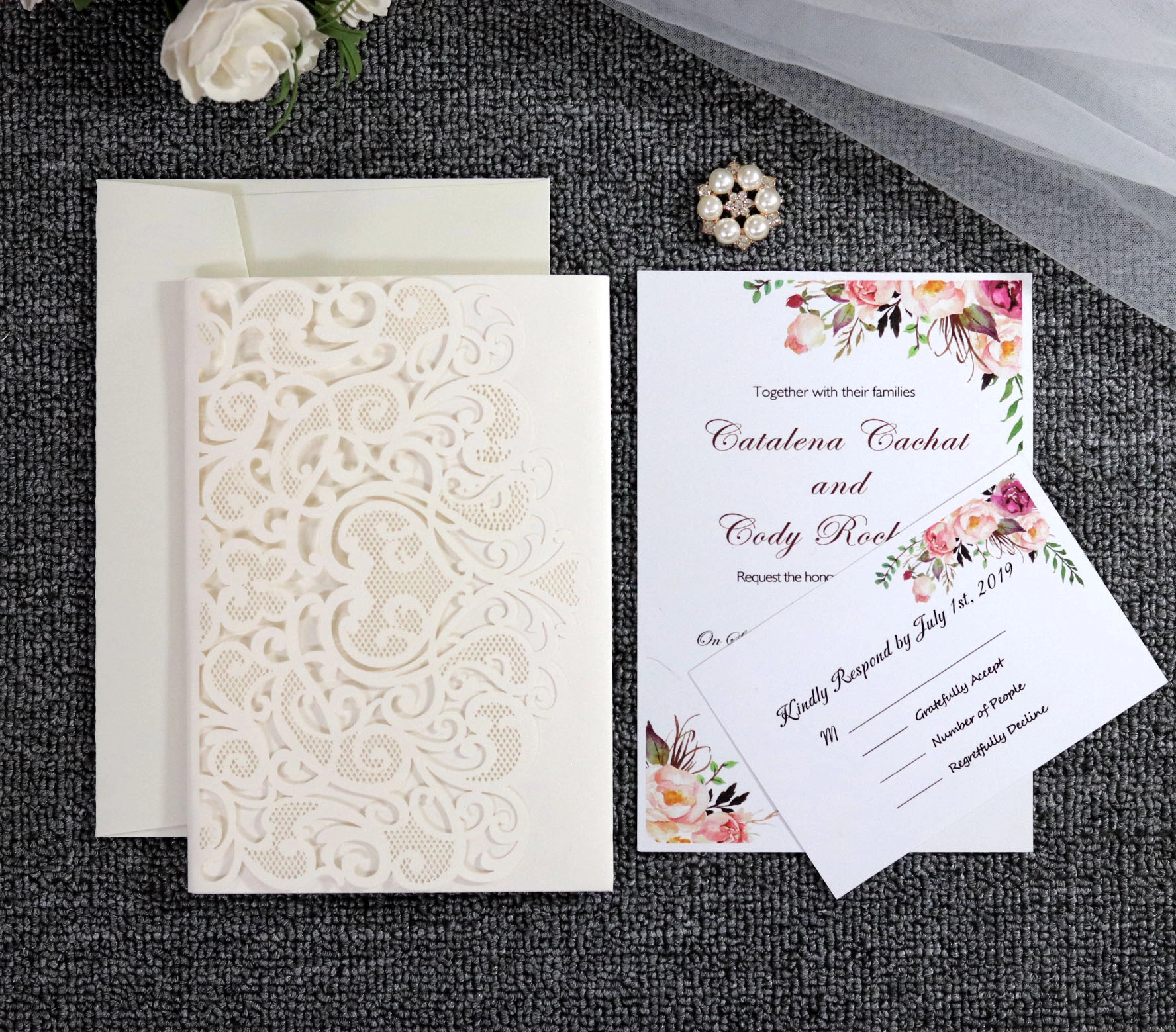 Elegant ivory laser-cut wedding invitation suite with floral RSVP insert.