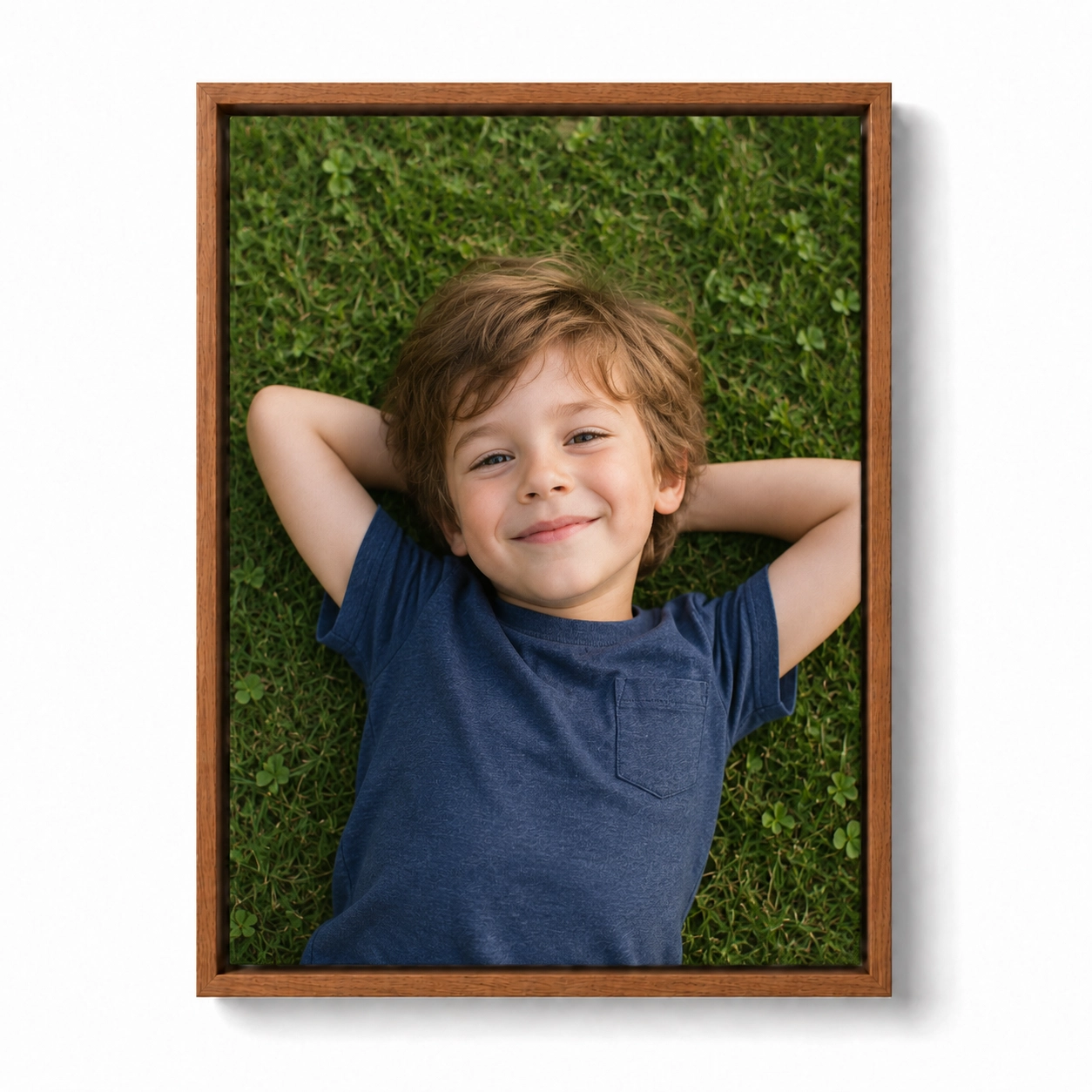 Custom walnut floating frame canvas print of a boy relaxing in lush green grass