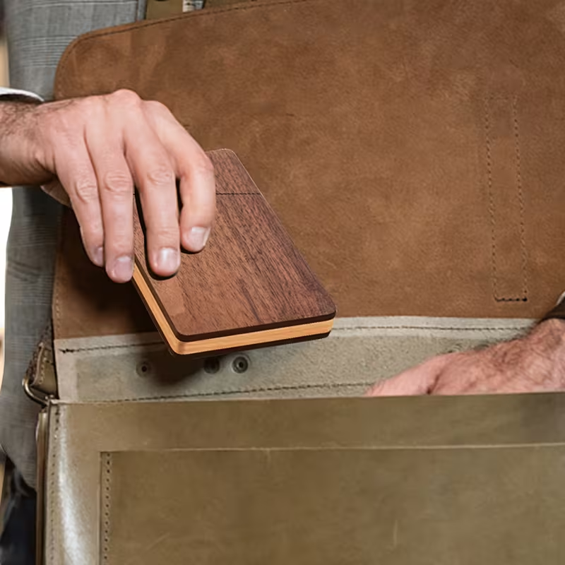 Personalized wood-grain card holder held over an open leather briefcase.